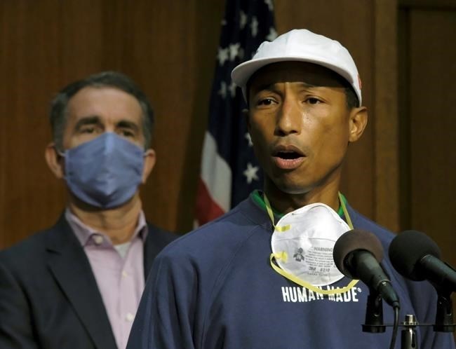 FILE - In this June 16, 2020, file photo, performing artist and Virginia native Pharrell Williams, right, speaks about the plan to make Juneteenth a state holiday as Virginia Governor Ralph Northam, left, listens during a press briefing inside the Patrick Henry Building in Richmond, Va. Juneteenth, the holiday that commemorates the end of slavery in the United States, originated 155 years ago. 