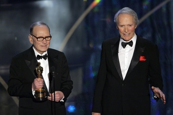 FILE - In this Feb. 25, 2007 file photo, Italian composer Ennio Morricone, left, accepts an honorary Oscar for his contributions to the art of film music as director Clint Eastwood looks on during the 79th Academy Awards telecast in Los Angeles. Morricone, who created the coyote-howl theme for the iconic Spaghetti Western “The Good, the Bad and the Ugly” and the soundtracks such classic Hollywood gangster movies as “The Untouchables,” died Monday, July 6, 2020 in a Rome hospital at the age of 91. 
