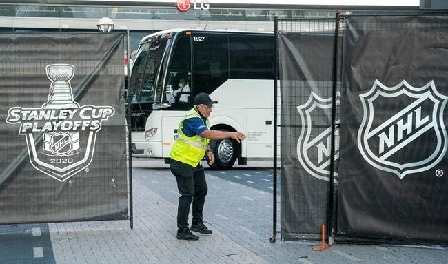 A security guard opens a gate for an empty player bus as it departs the Scotiabank Arena in Toronto on Thursday, Aug. 27, 2020.