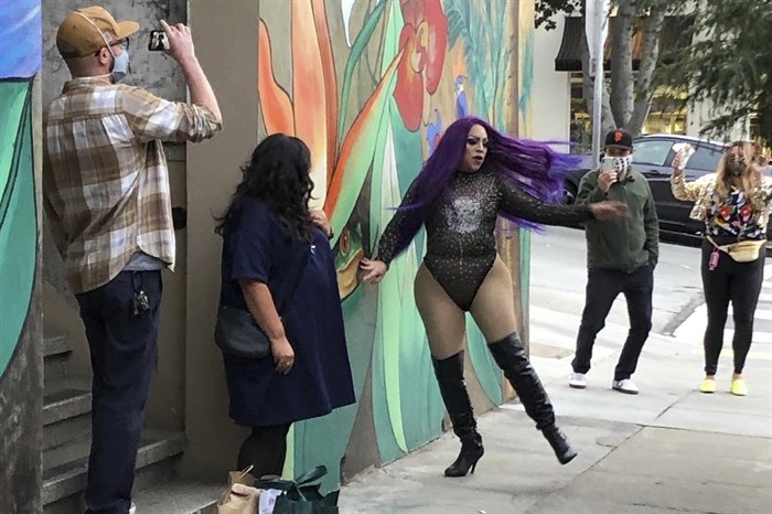 This Friday, Aug. 28, 2020, photo shows Amoura Teese, center, performing on a sidewalk for customers in San Francisco. A San Francisco drag show night club has taken the show on the road after having to close its doors due to the coronavirus pandemic. Oasis' 