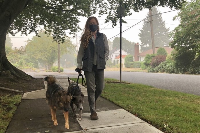 Zoe Flanagan walks her dogs amid dense smoke from wildfires in Portland, Ore., on Monday, Sept. 14, 2020. Wildfires across the U.S. West have created hazardous air quality in Portland and other West Coast cities.
