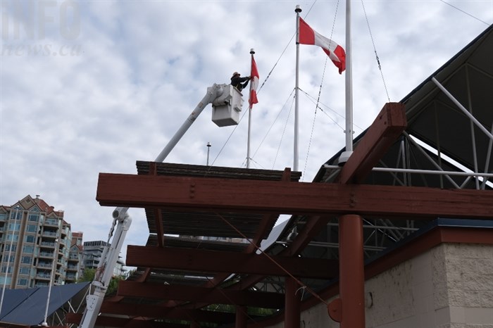 A Kelowna city worker removes a Canadian flag at Tugboat Bay.