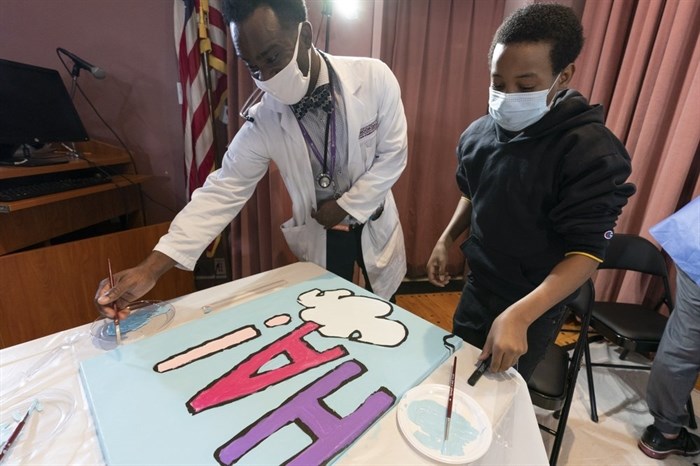 Pediatric resident Dr. Salome Wiredu, left and Jesse McCarty, 14, paint a panel of a 
