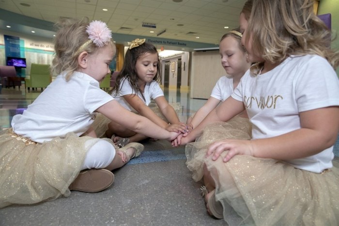 In this photo provided by Johns Hopkins All Children’s Hospital, Lauren Glynn, Chloe Grimes, McKinley Moore and Avalynn Luciano place their hands together at the hospital in St. Petersburg, Fla., Aug. 9, 2018. The girls, who were diagnosed with cancer in 2016 and became fast friends while undergoing treatment, reunite every year. 