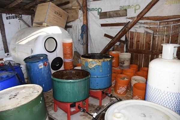 Various plastic and corroded metal containers containing waste.