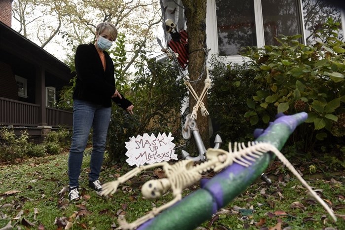 Carol McCarthy poses next to pirate-themed Halloween decorations reminding people to mask up while trick-or-treating during the COVID-19 pandemic, Monday, Oct. 26, 2020, in Palmyra, N.J. 