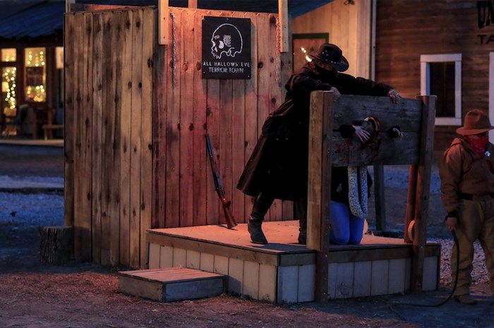 Cast member Dean Stout, left, puts a Terror Town visitor in a pillory, Saturday, Oct. 17, 2020, in Williamsburg, Ohio. 