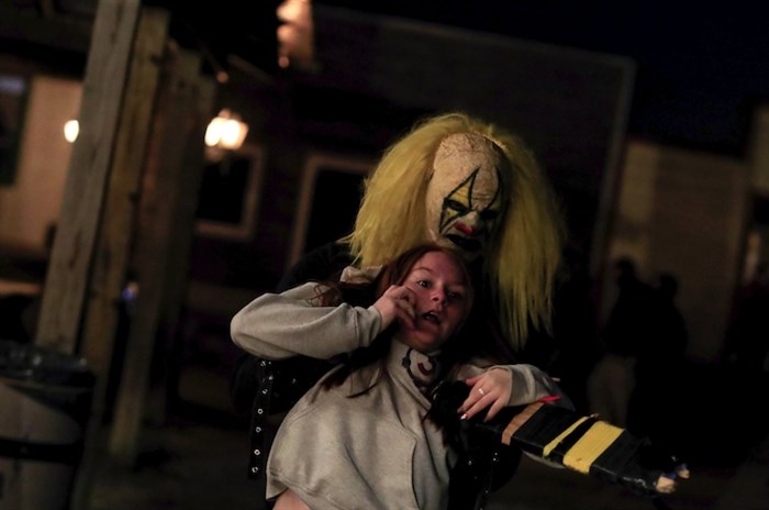 A cast member dressed as a clown grabs and drags away a visitor of Terror Town, Saturday, Oct. 17, 2020, in Williamsburg, Ohio. 