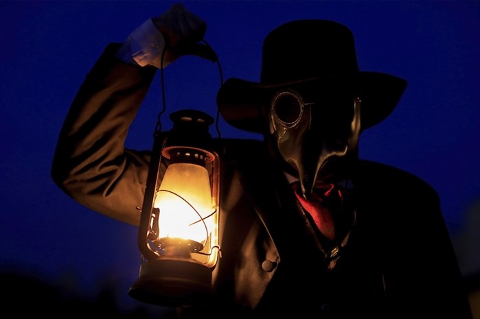 Co-Owner of Terror Town, James Gregory, holds a lantern as he wears a black plague mask while scaring visitors, Saturday, Oct. 17, 2020, in Williamsburg, Ohio. 