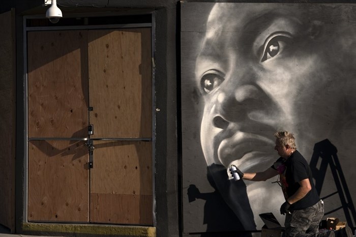 Artist Shane Grammer paints a portrait of Martin Luther King Jr. on the sheets of plywood outside a boarded-up jewelry shop amid worries about potential demonstrations and violent responses to the general election on Monday, Nov. 2, 2020, in Los Angeles. 