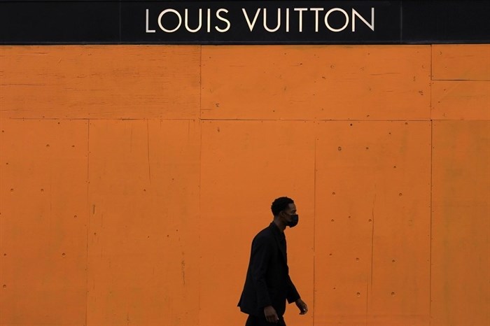 A man walks past a boarded-up window at a Louis Vuitton store in San Francisco, Sunday, Nov. 1, 2020, ahead of Election Day.