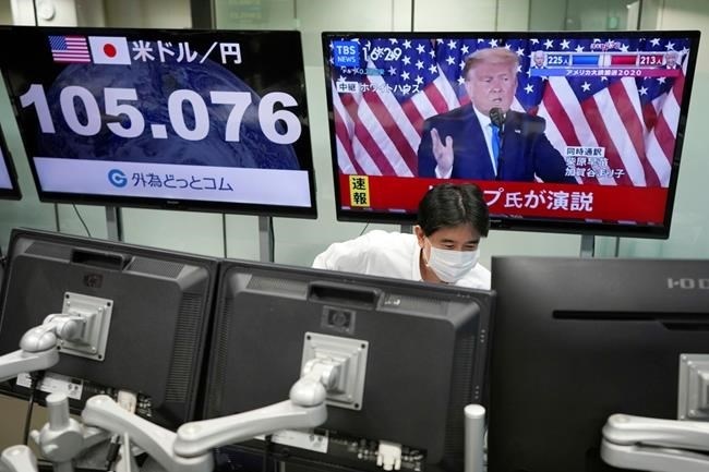 An employee works near a TV monitor showing a live broadcasting of the press conference by President Donald Trump, at a foreign exchange dealing company Wednesday, Nov. 4, 2020, in Tokyo. 