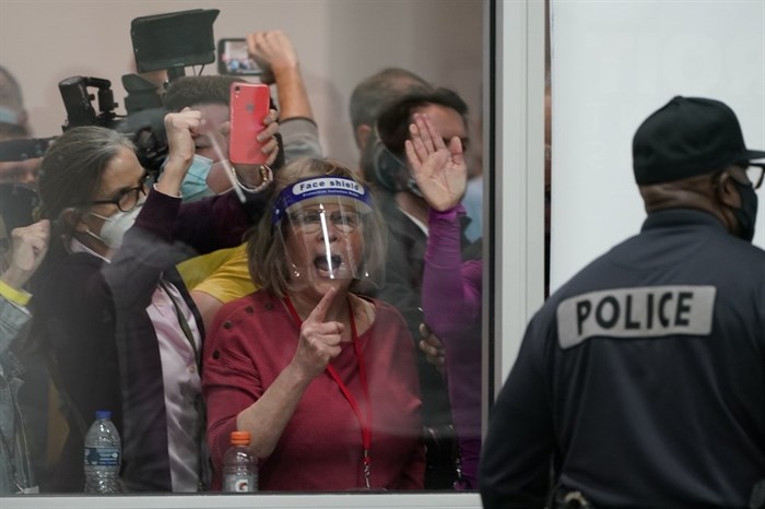 People yell as they look through the windows of the central counting board as police were helping to keep others from entering due to overcrowding, Wednesday, Nov. 4, 2020, in Detroit. 