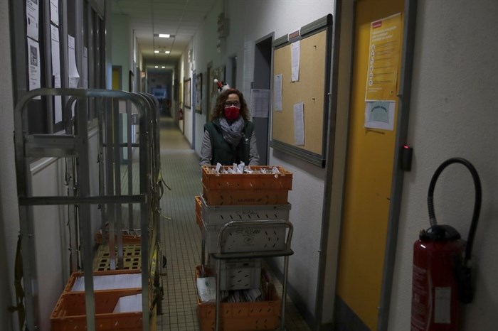 A postal worker brings a trolley of envelopes addressed to 