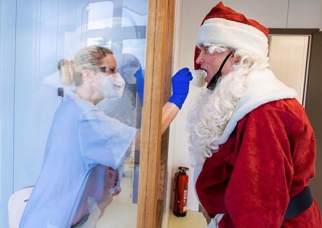 FILE - In this Dec. 21, 2020, file photo, Tessa Boulton, left, takes a swab test from Michael Kruse, dressed as Santa Claus, at a coronavirus testing center at the Helios Clinic in Schwerin, Germany. All most people wanted for Christmas after this year of pandemic was some cheer and togetherness. Instead many are heading into a season of isolation, grieving lost loved ones, experiencing uncertainty about their jobs or confronting the fear of a potentially more contagious variant of the coronavirus. 