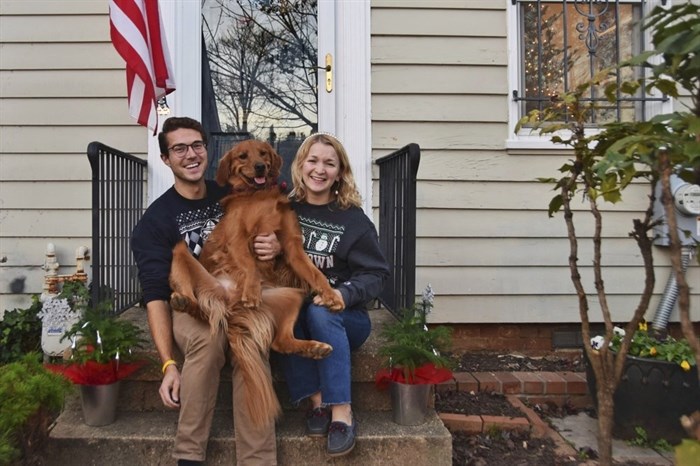 In this photo provided by Olivia Hinerfeld, Olivia Hinerfeld poses with her boyfriend, Ryan Shymansky, and their golden retriever Lincoln on Dec. 6, 2020, in Washington. Jealous of the attention that Hinerfeld is paying to her video conference call, Lincoln, will fetch “the most disgusting” tennis ball he can find from his toy crate to drop into the lap of the Georgetown University Law School student. 