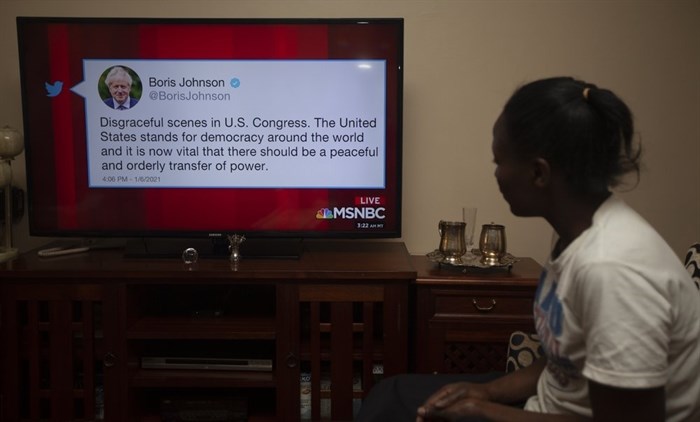 A Kenyan watches a news report on Kenyan TV, Thursday, Jan. 7, 2021, showing Britain's Prime Minister Boris Johnson Twitter comment among World leaders reaction to the U.S. Capitol demonstrations on Wednesday, Jan. 6, 2021, in Washington, USA.