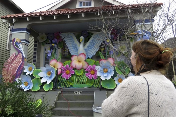 Designer, Caroline Thomas looks at a house decorated like a parade float in New Orleans on Friday, Jan. 8, 2021. All around the city, thousands of houses are being decorated as floats because the coronavirus pandemic has canceled parades that usually take place on Mardi Gras.