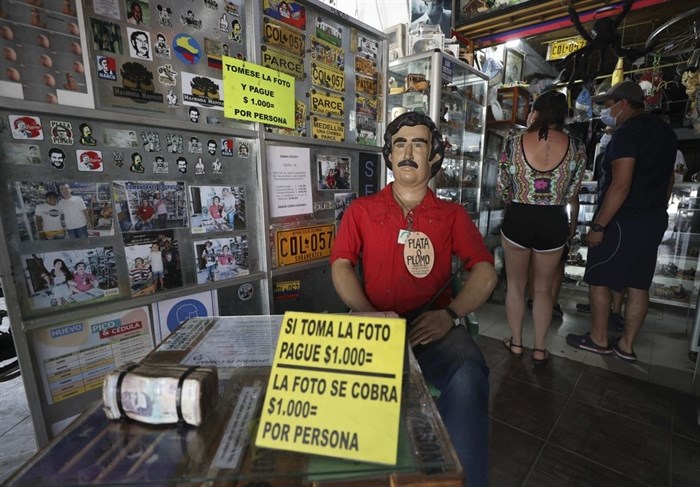 Tourists buy souvenirs of the late drug baron Pablo Escobar, featured as a statue with a sign that says one will be charged for taking photos inside a store in Doradal, Colombia, Friday, Feb. 5, 2021. Escobar and his Medellin Cartel are long dead, but one of the zoo’s prized specimens is flourishing in the tropical countryside and wetlands in and around the palace-turned-theme park — the hippopotamus.