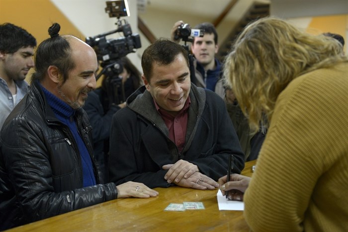Rodrigo Borda, left, and his partner Sergio Miranda watch a Civil Registry worker take down their information to apply to get married in Montevideo, Uruguay, Monday, Aug. 5, 2013. 
