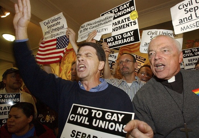 The Rev. Joshua Cotter, of the Unification Church in Bridgeport, Conn., center, an opponent of same-sex marriage, and George Welles, of the Church of Our Savior, in Milton, Mass., right, a supporter of same-sex marriage, at the Massachusetts Statehouse in Boston on Monday, March 29, 2004. Demonstrators from the rival sides were urging lawmakers to vote their way. No marriage legislation took effect at that time; same-sex marriage began in Massachusetts in May 2004 under an order from the state Supreme Court. 
