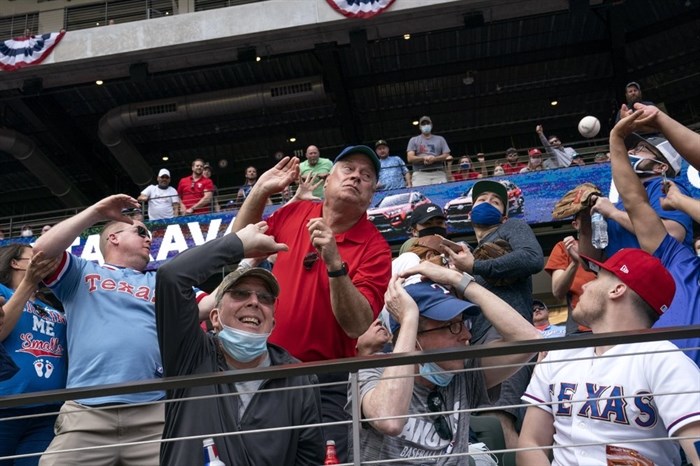 Fans scramble for a foul ball during the first inning of a baseball game between the Texas Rangers and the Toronto Blue Jays, Monday, April 5, 2021, in Arlington, Texas.