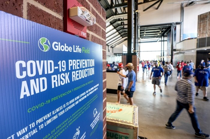 A COVID-19 prevention protocol sign hangs in the concourse of Globe Life Field before the Texas Rangers home opener baseball game against the Toronto Blue Jays Monday, April 5, 2021, in Arlington, Texas. The Texas Rangers are set to have the closest thing to a full stadium in pro sports since the coronavirus shut down more than a year ago. 