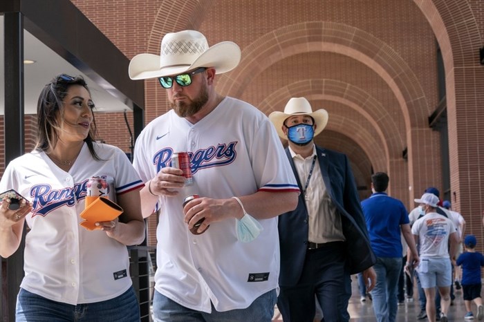 Josh Johnson and Zoe Aguilar walk through the concourse of Globe Life Field before the Texas Rangers home opener baseball game against the Toronto Blue Jays Monday, April 5, 2021, in Arlington, Texas. The Texas Rangers are set to have the closest thing to a full stadium in pro sports since the coronavirus shut down more than a year ago. 