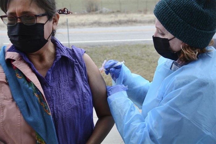 In this Thursday, April 29, 2021, photo, Sherry Cross Child, a Canadian resident of Stand Off, Alberta, receives a COVID-19 vaccine at the Piegan-Carway border crossing near Babb, Mont. The Blackfeet tribe in northern Montana gave out surplus vaccines in April to its First Nations relatives and others from across the border.