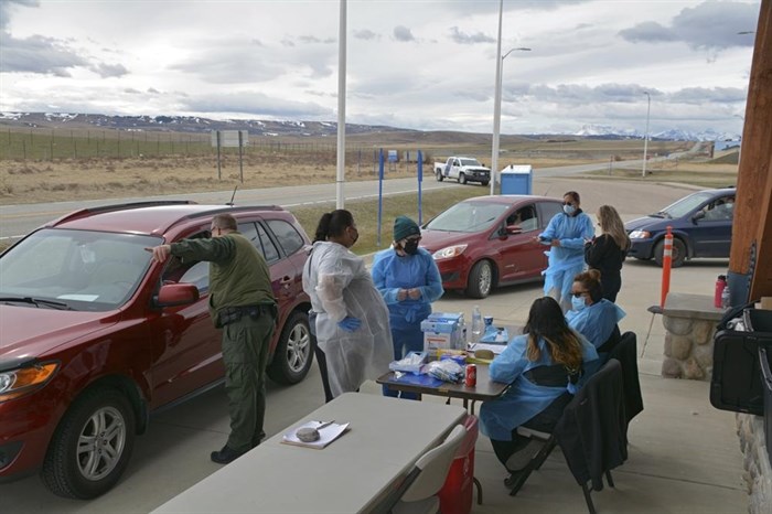 In this Thursday, April 29, 2021, photo, a U.S. Border Patrol agent directs a driver after the passenger received a COVID-19 vaccine from nurses of the Blackfeet tribe at the Piegan-Carway border crossing near Babb, Mont. The Blackfeet tribe in northern Montana gave out surplus vaccines in April to its First Nations relatives and others from across the border.