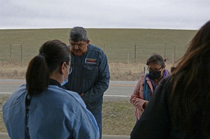In this Thursday, April 29, 2021, photo, Sherry Cross Child and Shane Little Bear, residents of Stand Off, Alberta, recite a prayer ahead of a vaccination clinic held in Montana for Canadian residents at the Piegan-Carway border crossing near Babb, Mont. The Blackfeet tribe gave out surplus vaccines to its First Nations relatives and others from across the border.
