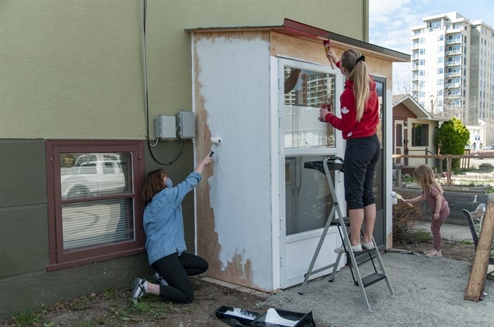 Volunteers paint a shed that houses the Kelowna Community Fridge at the Kelowna Unitarian church.