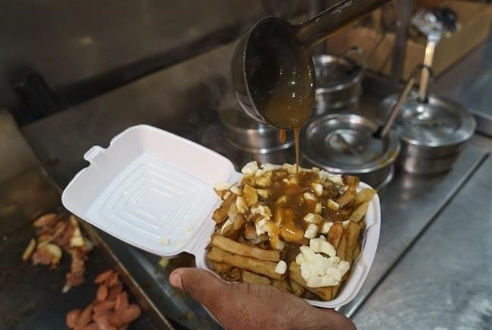 A cook prepares a poutine at La Banquise restaurant in Montreal on Tuesday, May 18, 2021. The Quebec dairy industry trying to get a protected trademark for the popular Quebecois dish.