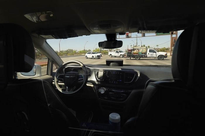 A Waymo minivan moves along a city street as an empty driver's seat and a moving steering wheel drive passengers during an autonomous vehicle ride, Wednesday, April 7, 2021, in Chandler, Ariz. Waymo, a unit of Google parent Alphabet Inc., is one of several companies testing driverless vehicles in the U.S. But it's the first offering lifts to the public with no humans at the wheel who can take over in sticky situations.