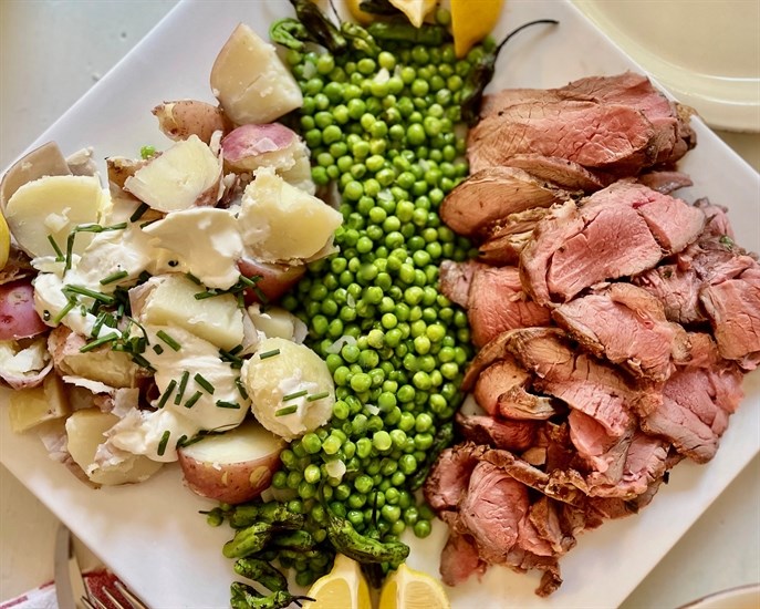 A platter featuring greek lamb, minted peas and new potatoes.