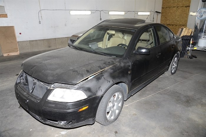 Photo of a black Volkswagen Passat vehicle. The hood of the vehicle is partially opened and missing the front grill