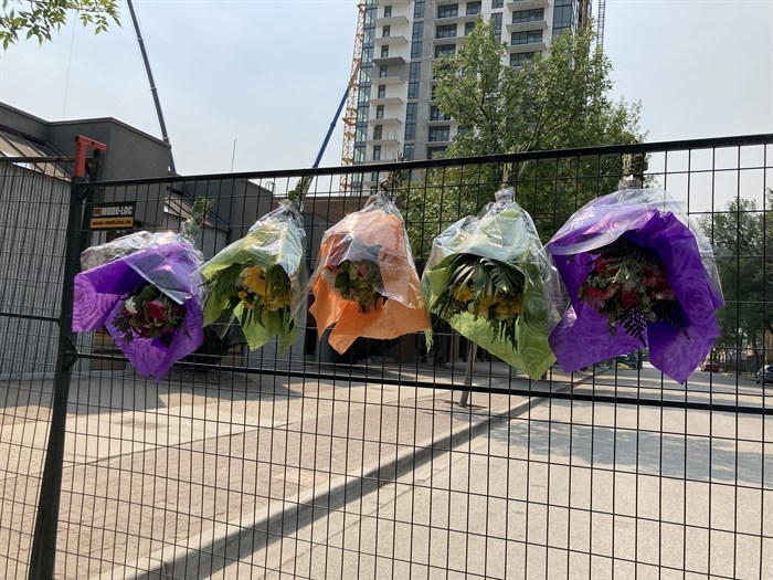Five flower bouquets have been hung on a fence at the site of a crane collapse in downtown Kelowna that claimed five lives, July 14, 2021.