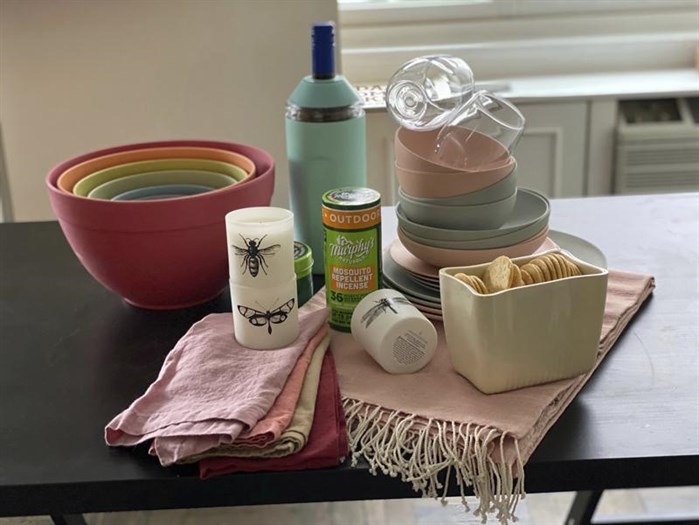 This image provided by Katie Workman shows colorful bamboo plates and bowls, stylish acrylic wine glasses, a sleek wine chiller, a cozy throw for cooler nights, and smart bug-repelling gear. These are just a few ways you can amp up your outdoor entertaining this summer. 