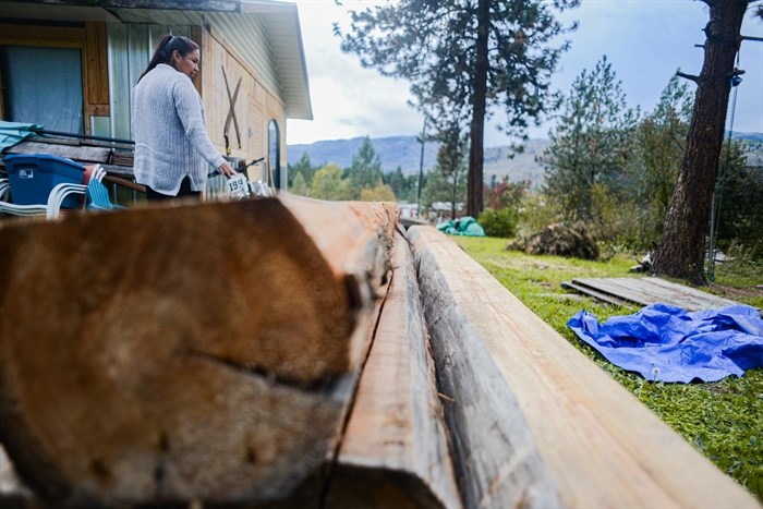 Miranda Dick, Secwépemc Matriarch, walks by the logs the family selected and harvested for the ceremony lodge.