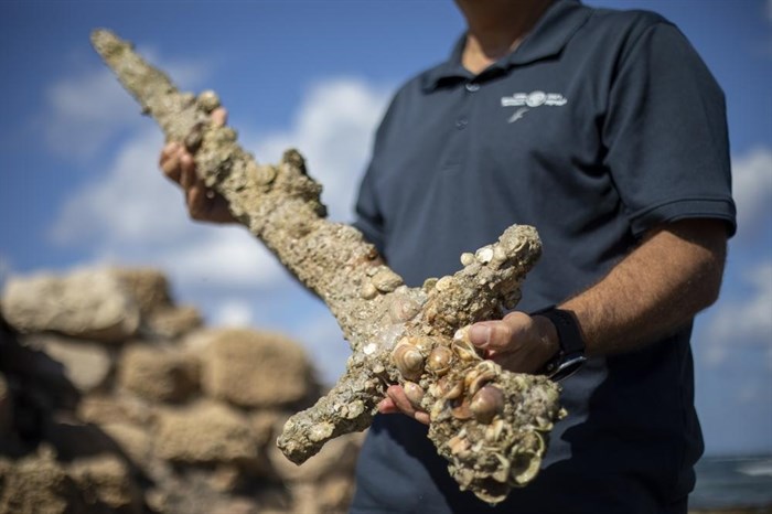 Jacob Sharvit, director of the Marine Archaeology Unit of the Israel Antiquities Authority, holds a meter-long (yard-long) sword, that experts say dates back to the Crusaders, in the Mediterranean seaport of Cesarea, Israel, Tuesday, Oct. 19, 2021.
