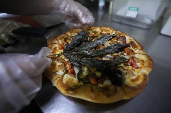 A staff member decorates a pizza with a deep fried cannabis leaf at a restaurant in Bangkok, Thailand on Nov. 24, 2021. The Pizza Company, a Thai major fast food chain, has been promoting its "Crazy Happy Pizza" this month, an under-the-radar product topped with a cannabis leaf. It’s legal but won’t get you high.