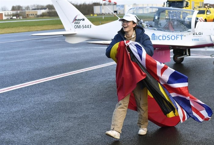 Belgium-British teenage pilot Zara Rutherford walks on the tarmac with a British and Belgian flag after landing her Shark ultralight plane at the Kortrijk airport in Kortrijk, Belgium, Thursday, Jan. 20, 2022.