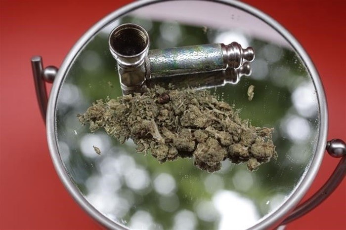 FILE - Marijuana and a pipe used to smoke it are displayed on a mirror in New York on June 20, 2018. While New York works on launching a legal market for recreational marijuana, some entrepreneurs have jumped into a legal grey area by saying they're not selling pot but giving it away while people buy something else.