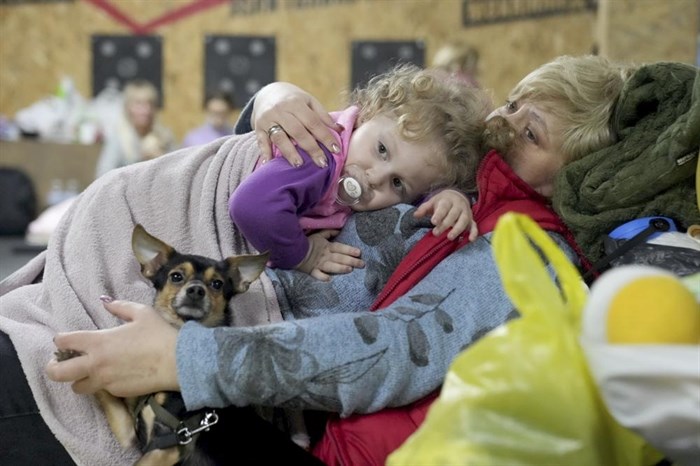 A women holds a child and a dog in a shelter inside a building in Mariupol, Ukraine, Sunday, Feb. 27, 2022. Street fighting broke out in Ukraine's second-largest city and Russian troops squeezed strategic ports in the country's south as the prospect of peace talks remains uncertain.