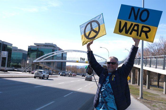 Penticton resident Gordon De Roos waves signs showing his support for Ukraine in Kelowna, March 6, 2022. 