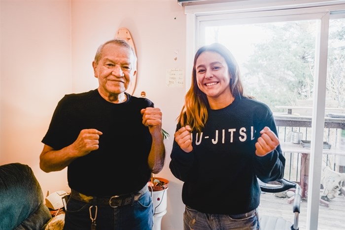 Freddy Louis and Rylie Marchand, OKIB fighters of past and present, stand with their fists up, in Freddy’s living room, after swapping ring stories.