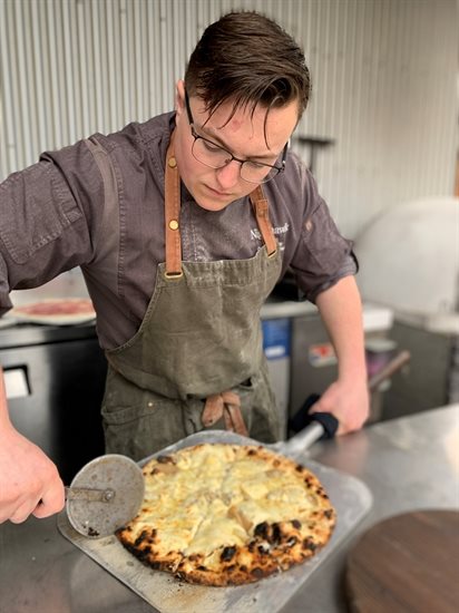 Chef Carson Bibby, of Nighthawk Vineyards, slices a pizza for guests.