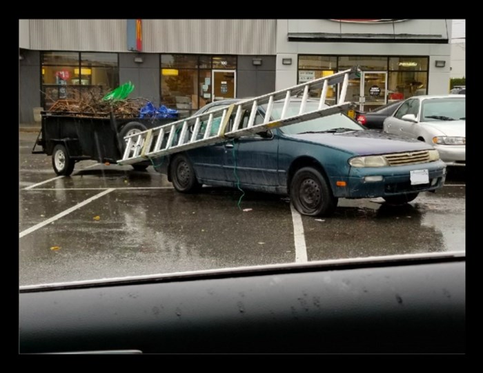 This driver had a ladder dangling off of their sedan, an improperly secured load in the trailer, a flat tire, while taking up numerous parking spaces.
