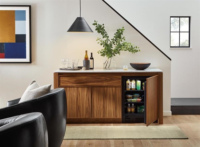 This image released by Amherst Cabinets shows a walnut cabinet that can work as a resting spot for a TV, books or art objects, while the interior is a handy fridge. The top comes in a variety of colors in granite or quartz.