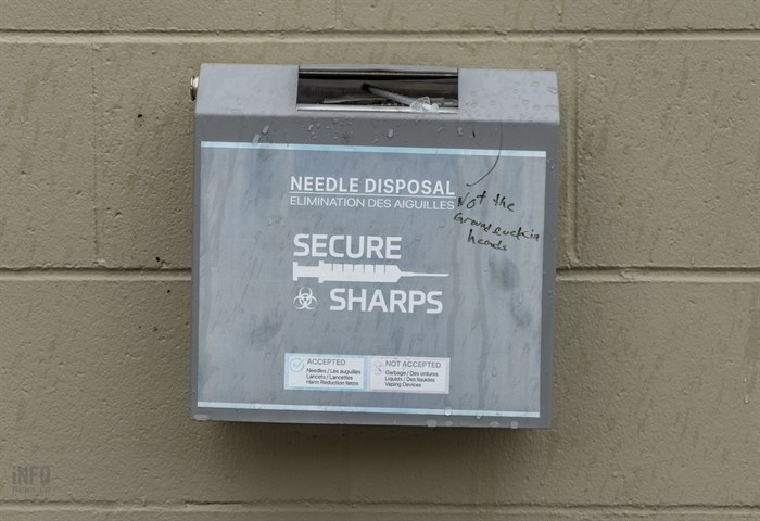A needle disposal box is located in an alley where drug users are known to frequent.